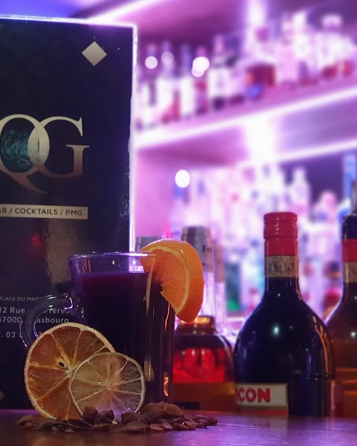 Un vin chaud à l'orange devant la carte noire et or du QG
